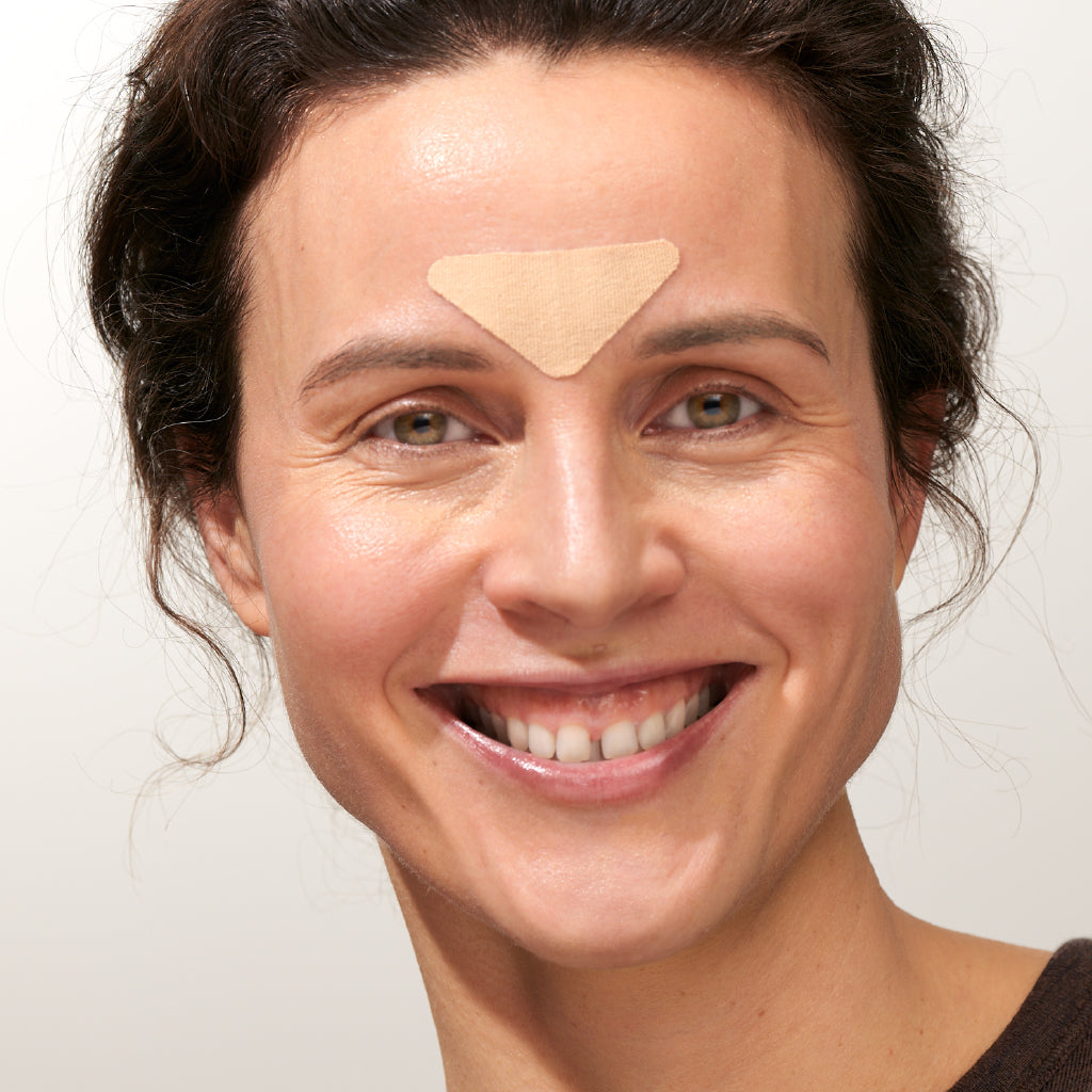 Model trägt APRICOT Zornesfalten Patches mit Hyaluron aus Bio-Baumwolle für die Stirnpartie